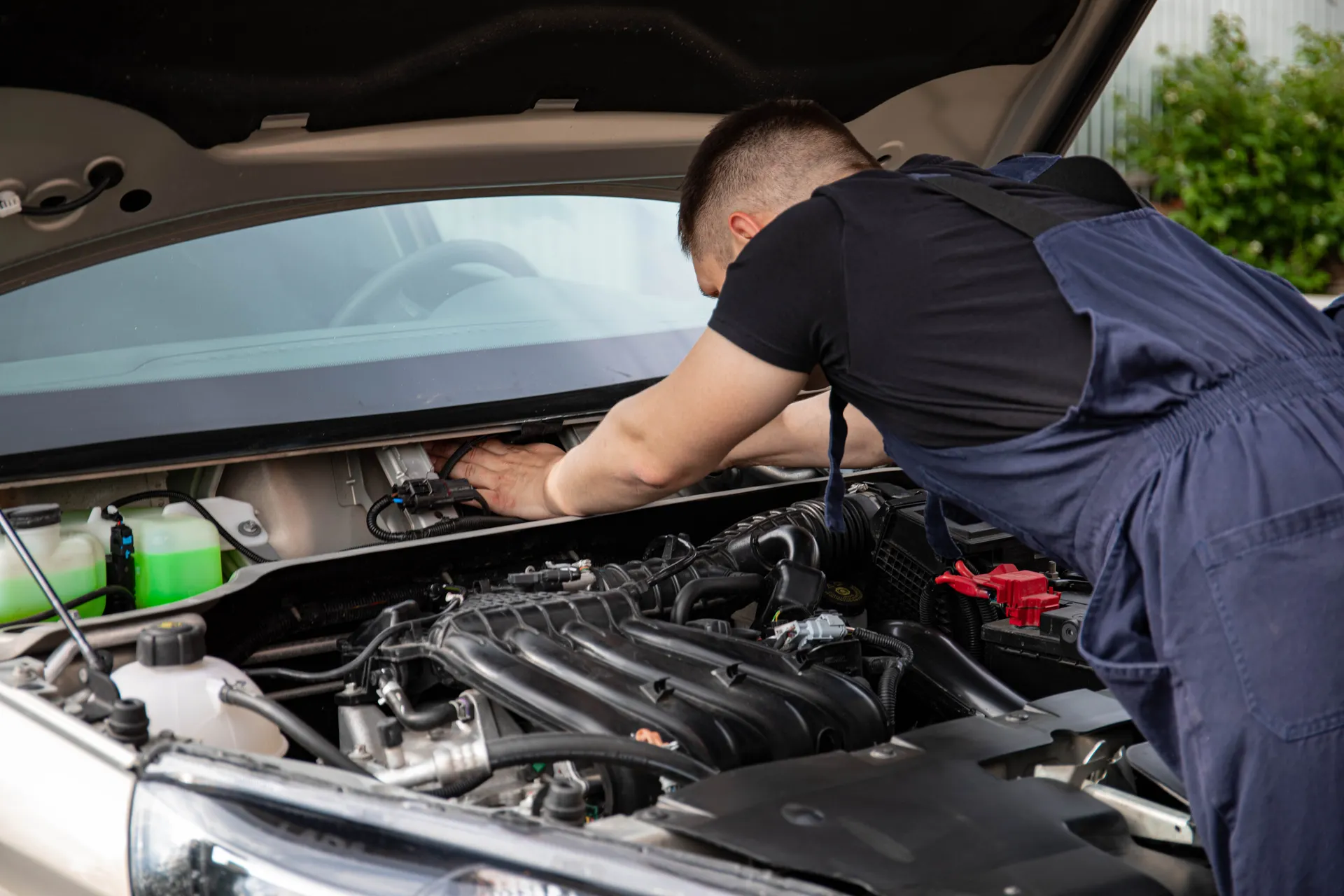 Technician working under the hood of a car at an auto repair shop