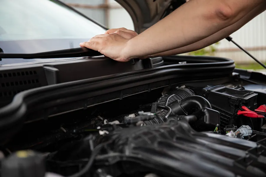 Technician working in the engine bay of a vehicle with the hood raised