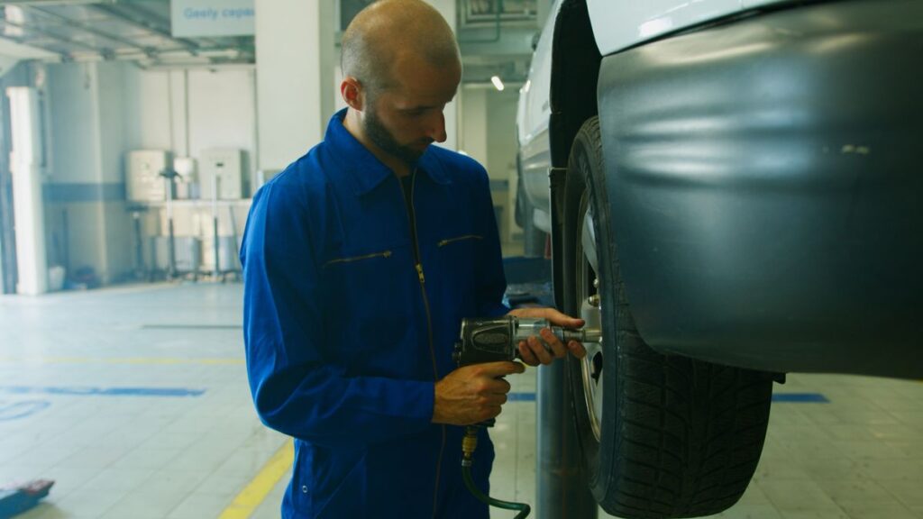 Mechanic using an impact wrench on a car wheel