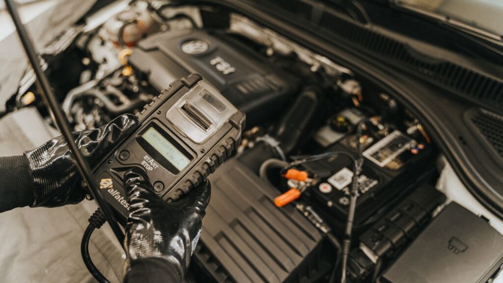 Car electrical repair in Grand Rapids: mechanic using a handheld diagnostic tool in a car engine bay