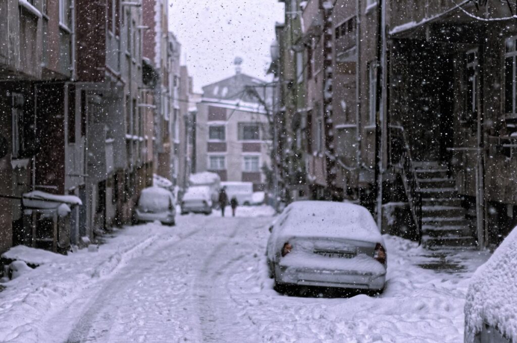 Snow-covered cars on a city street