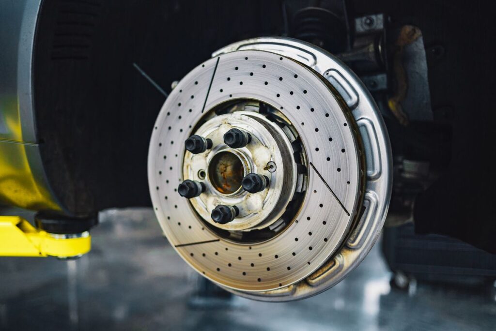 Drilled brake rotor on a car with the wheel removed in a workshop
