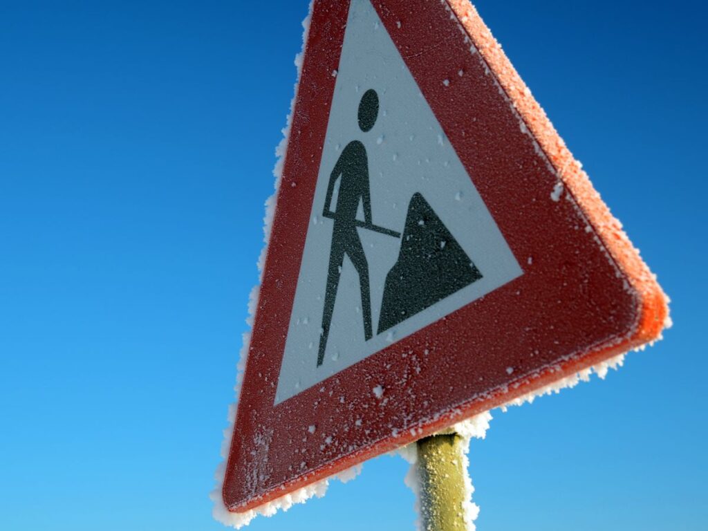 Frost-covered road sign against a blue sky