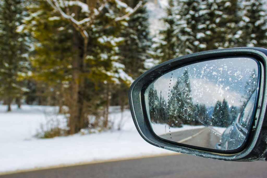 Side mirror reflecting a snowy road