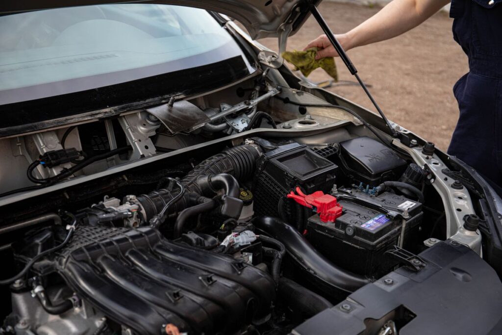 Mechanic checking a car's battery and engine bay during maintenance
