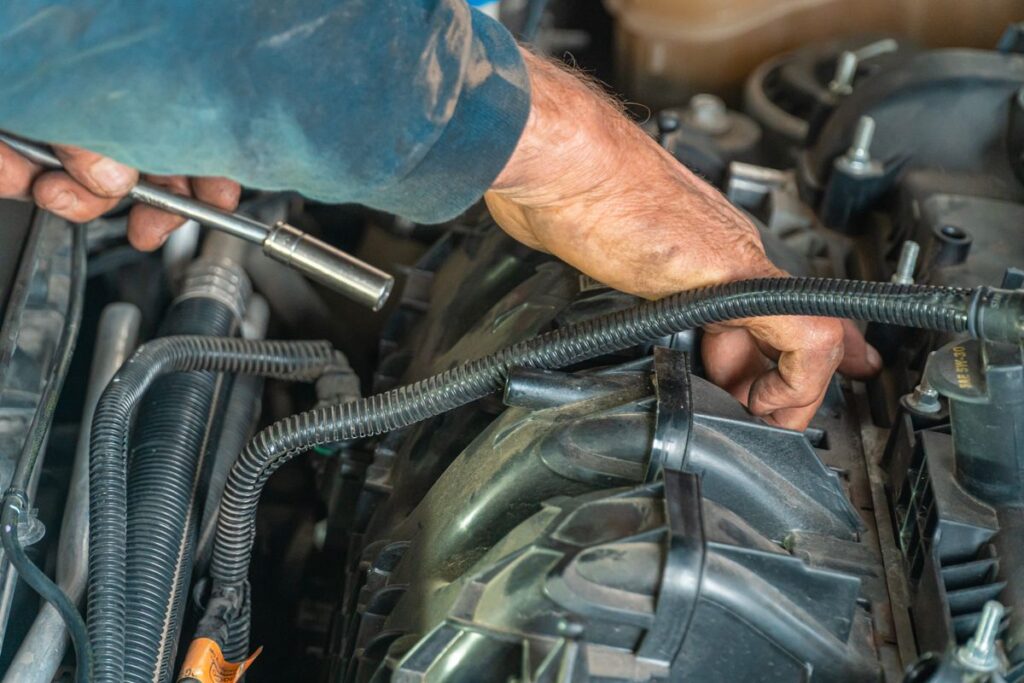 Mechanic's hands working on a car engine with a ratchet