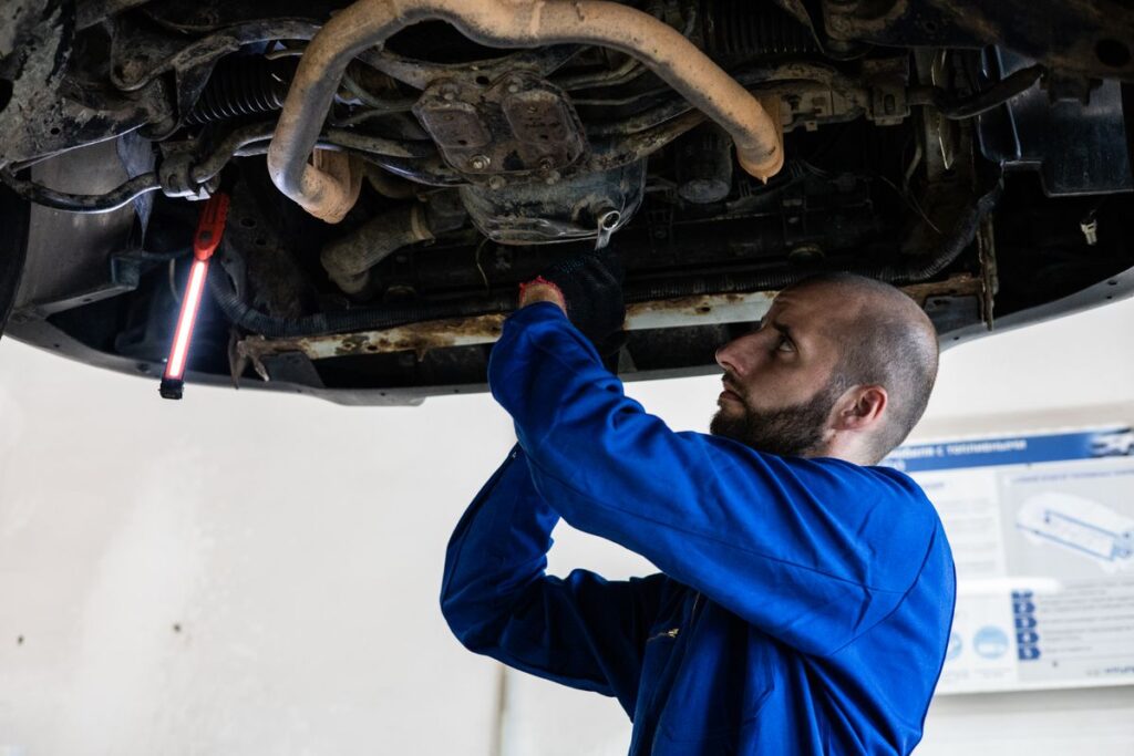 Mechanic inspecting the exhaust under a car