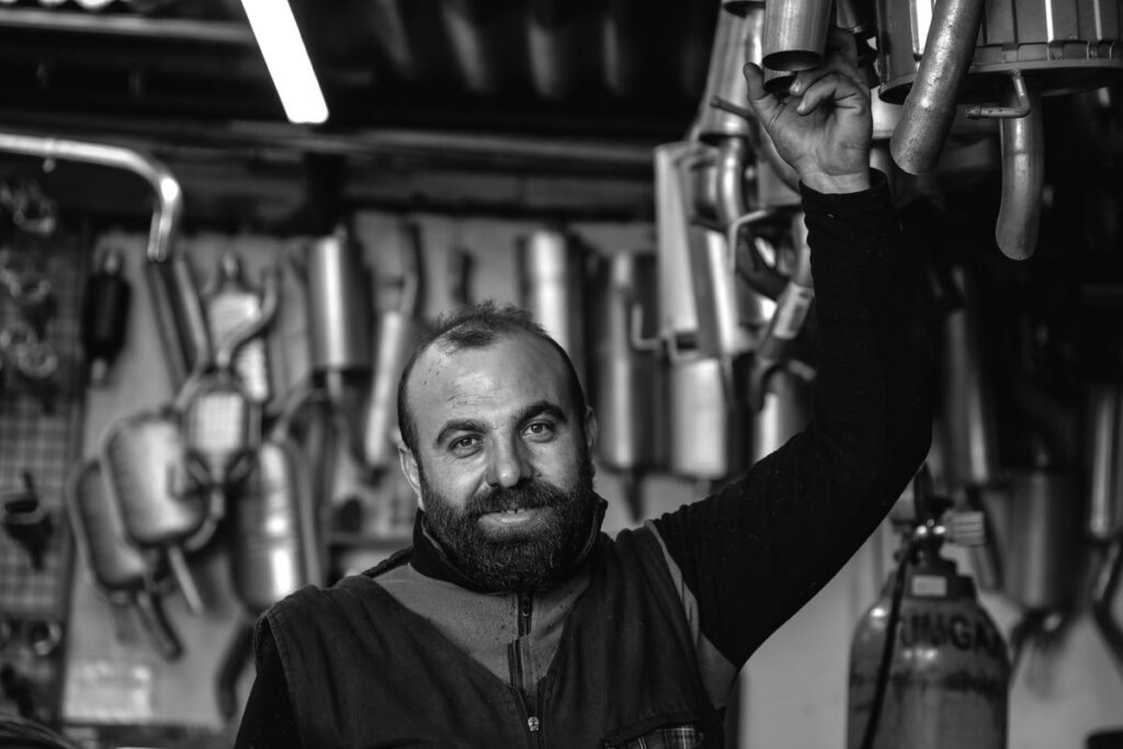 Mechanic beside a wall of exhaust parts