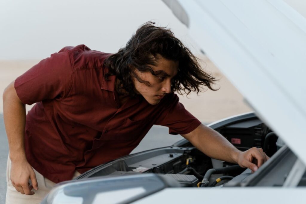 Man checking under a car's hood
