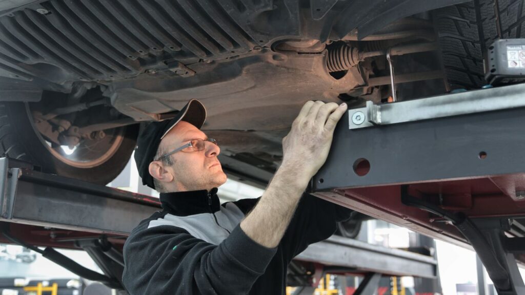 Pre-purchase inspection in Grand Rapids: mechanic inspecting the underside of a car raised on a lift