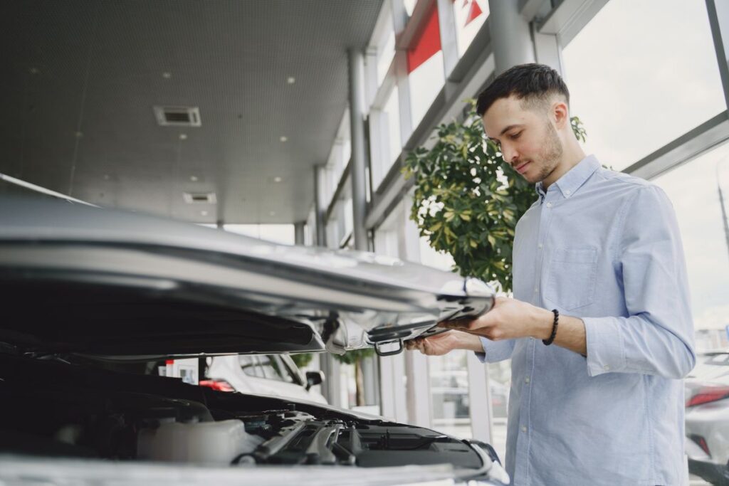 Buyer checking the engine of a used car at a dealership