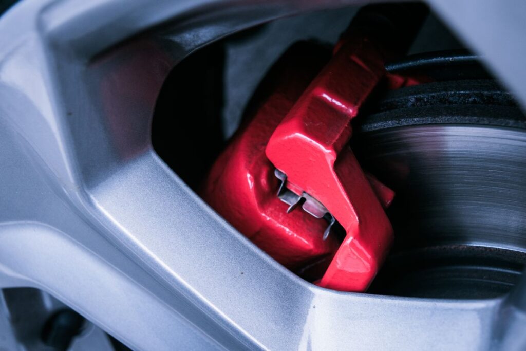 Red brake caliper and rotor behind a car wheel