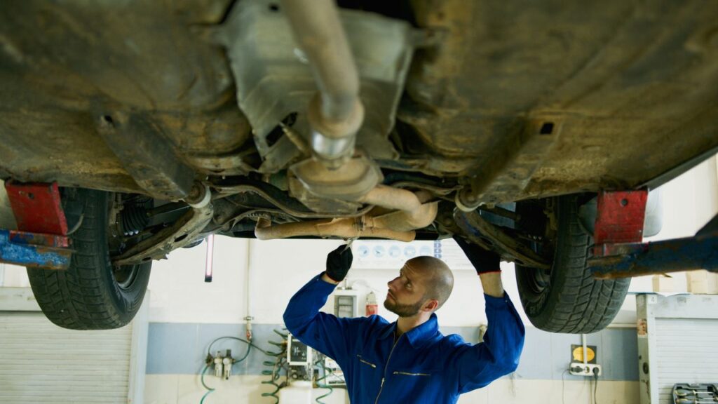 Road salt brake line rust in Michigan: mechanic examining the underside of a car in a repair shop