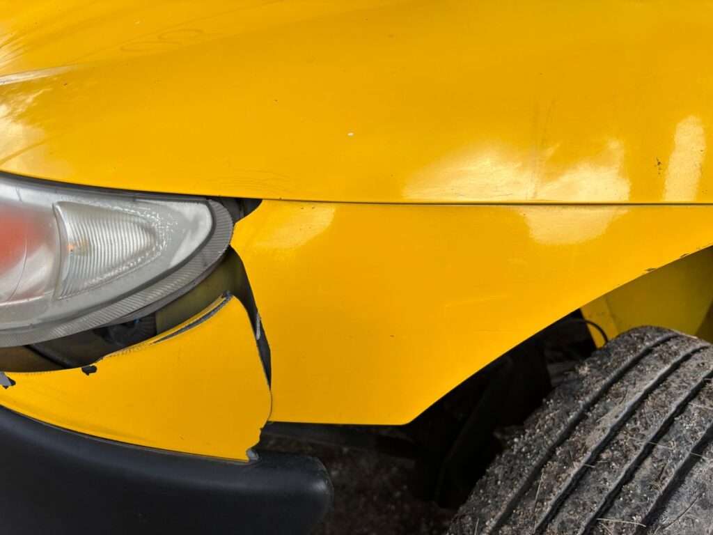 Damaged front bumper and headlight on a yellow car