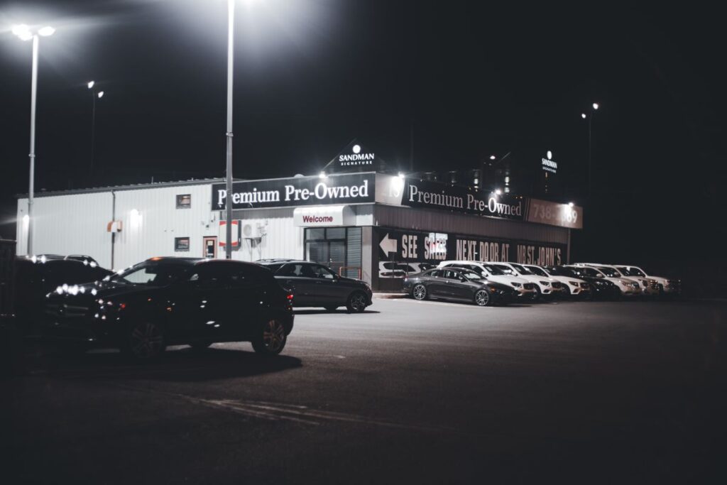 Pre-owned car dealership lot lit up at night