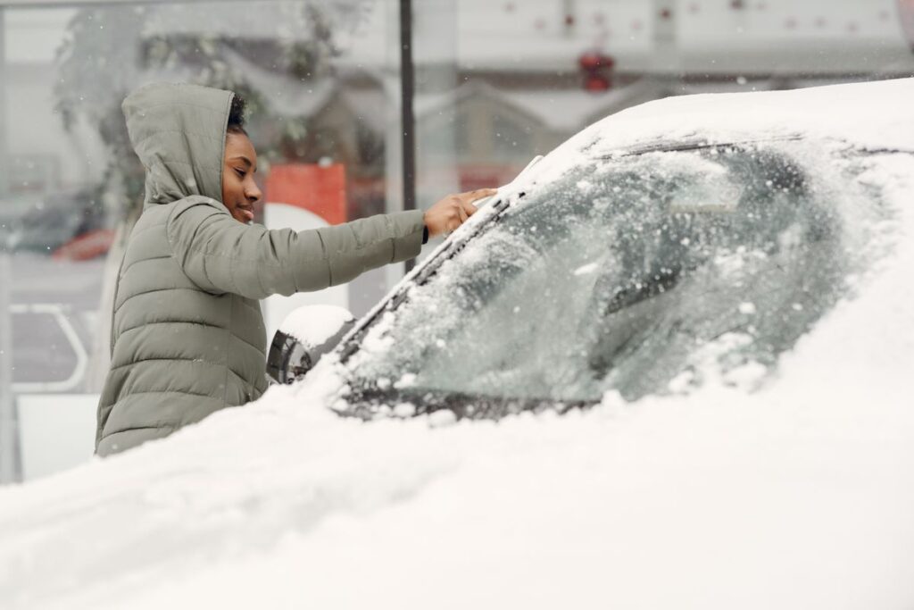 Person clearing snow off a windshield